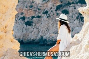 Cómo atraer mujeres: chica sexy sentada sobre un roca mirando hacia el mar. 