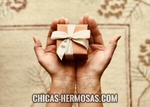 Mujeres guapas: Regalo para mujer Mujeres guapas: La imagen muestra las manos de una mujer sosteniendo un regalo. Mujeres se emocionan al recibir regalos de sus parejas.