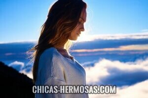 Relaciones exclusivas: Belleza Relaciones exclusivas: Una mujer visualizada de lado. Esta posando al borde de un acantilado. Al fondo se ven nubes, el resplandor del sol y el horizonte. Un momento de suspiro y un mensaje profundo.
