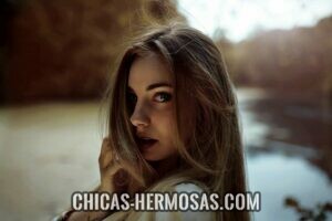 Relaciones exclusivas: chica hermosa posando Relaciones exclusivas: El retrato de una mujer más joven, atractiva y sensual. Esta jugando con la cámara y oculta parte de su rostro. Un gesto muy coqueto y juguetón.