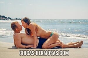 Relaciones exclusivas: momento apasionado Relaciones exclusivas: En la imagen vemos una pareja teniendo un momento apasionado. Están disfrutando de un día de playa. Mientras él esta acostado sobre su espalda, ella está sobre el acercándose para darle un beso.